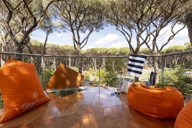 Spazio all'aperto con cuscini arancioni e alberi.