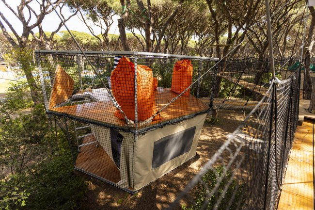 Casetta sospesa su struttura di rete in un bosco.