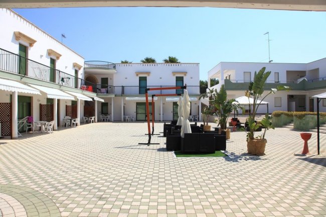 Cortile con sedie, tavoli e piante verdi.