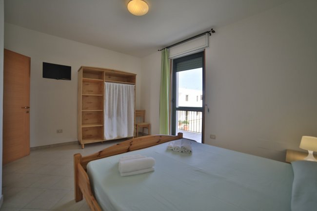 Una camera da letto con letto matrimoniale, finestra, armadio e TV a parete.