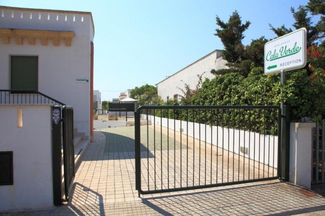 Ingresso con cancello nero e cartello della reception 