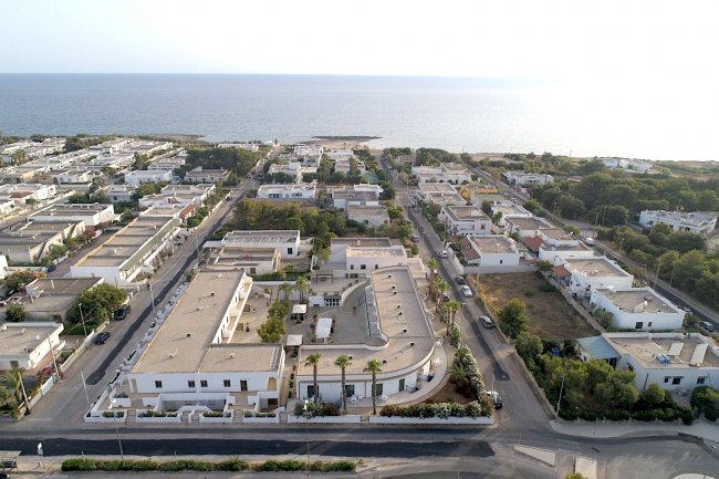Vista aerea di un quartiere residenziale costiero con il mare sullo sfondo.