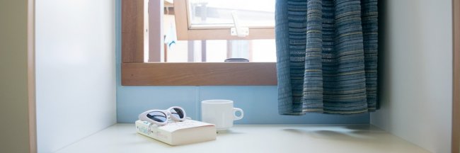 Finestra aperta, occhiali e tazza su un tavolo.