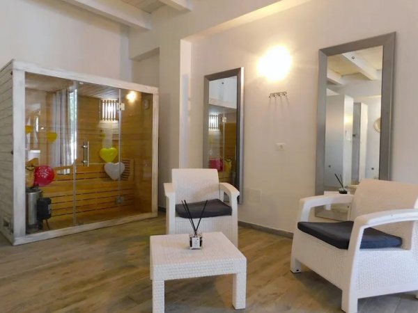 Area relax con poltrone bianche e sauna in legno.