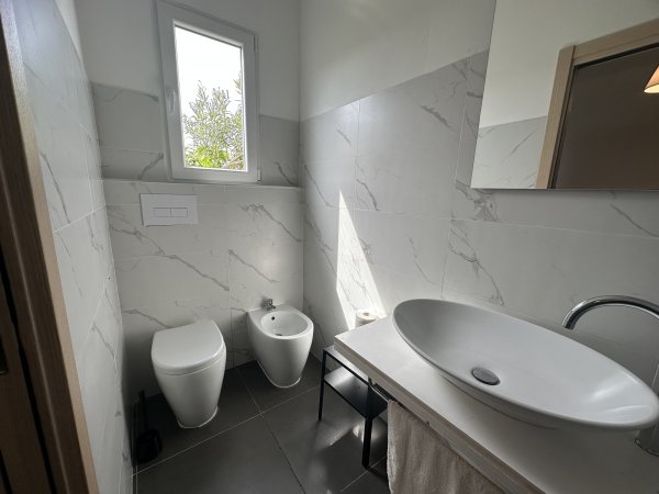 Bagno moderno con sanitari bianchi e lavabo.