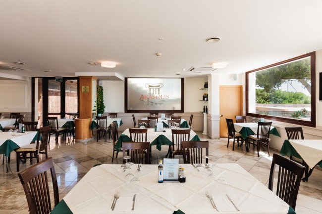 Sala ristorante con tavoli apparecchiati e grande finestra.