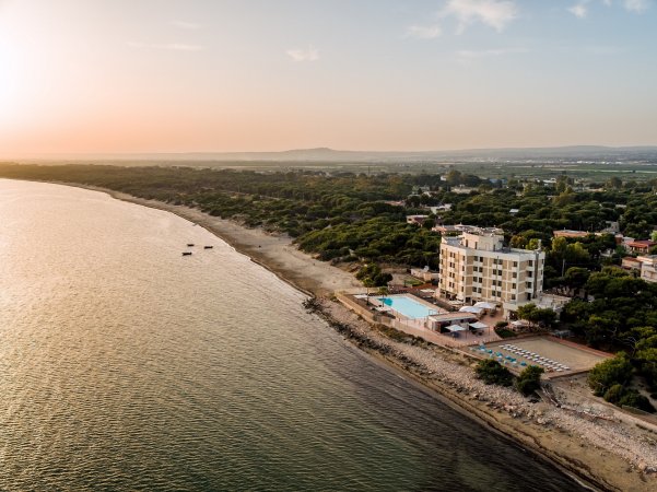 Spiaggia al tramonto con hotel e piscina sulla costa.