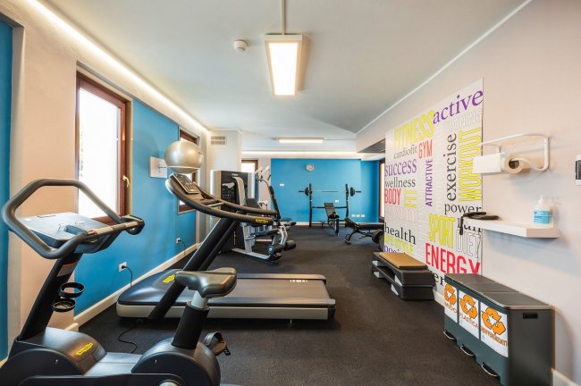 Palestra moderna con attrezzature e parete colorata.