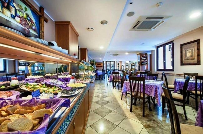 Ristorante con buffet ricco e tavoli apparecchiati con tovaglie viola.