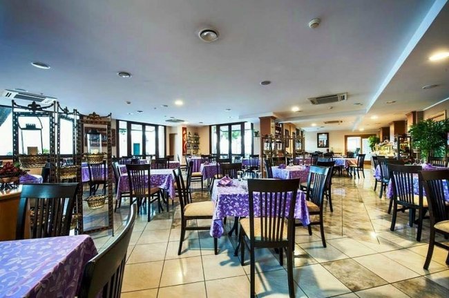 Una sala ristorante con tavoli apparecchiati con tovaglie viola.