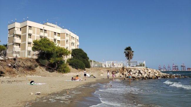 Una spiaggia con alcune persone e un grande edificio sullo sfondo.