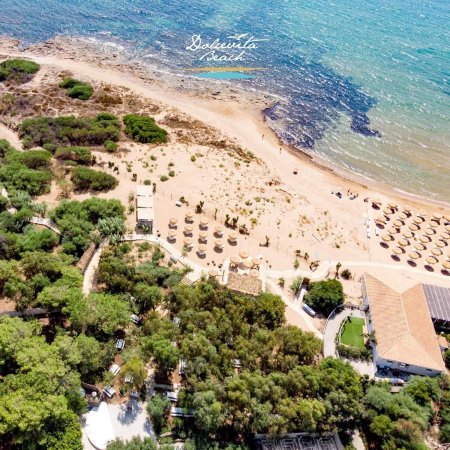 Vista aerea di una spiaggia con ombrelloni e mare azzurro.