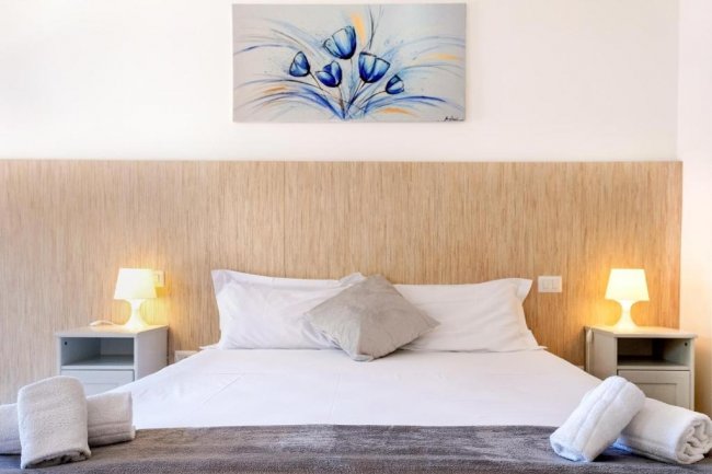 Letto con lenzuola bianche e quadri blu sopra.