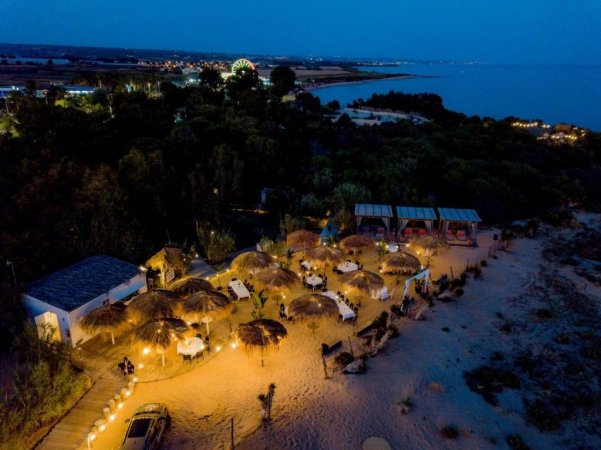 Veduta aerea di un'area spiaggia illuminata di notte, con ombrelloni.