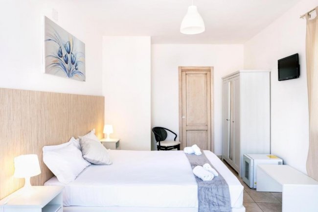Interno di una camera da letto luminosa con letto matrimoniale e arredo moderno.