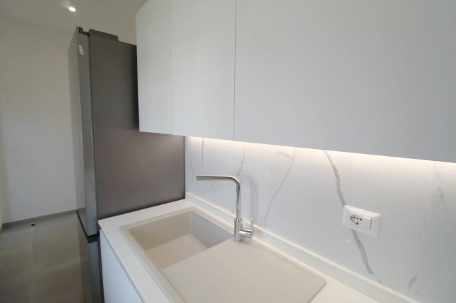 Cucina moderna con mobili bianchi e lavabo.