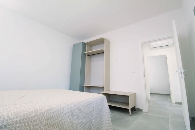 Camera minimalista con letto e armadio.