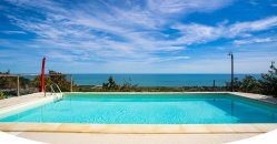 Piscina limpida con vista sull'oceano e cielo blu.