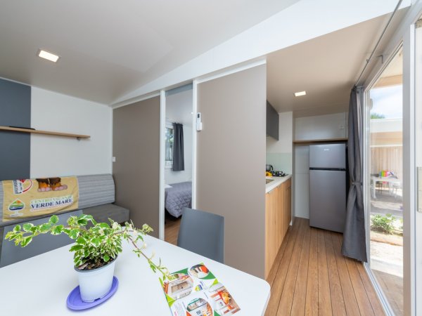 Interno moderno con tavolo, pianta e cucina.