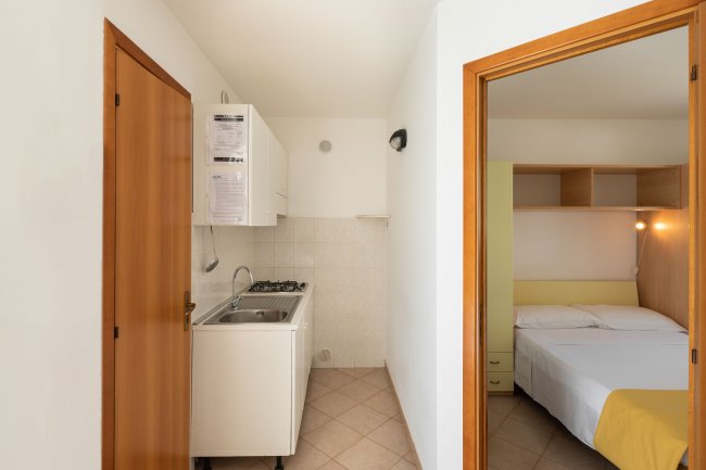 Angolo cottura con lavabo e vista su camera da letto.