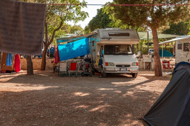 Camper parcheggiato tra gli alberi in un'area campeggio.