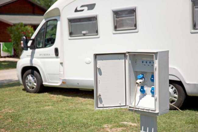 Un camper parcheggiato accanto a una colonnina elettrica aperta.