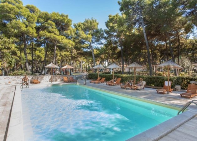 Piscina all'aperto circondata da lettini e ombrelloni.