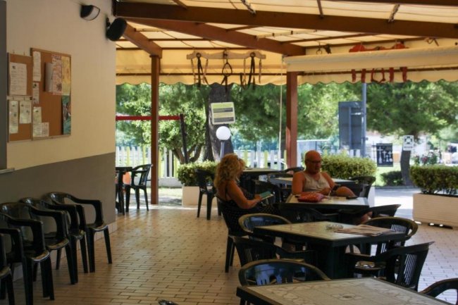 Veranda con tavoli e persone sedute all'aperto.