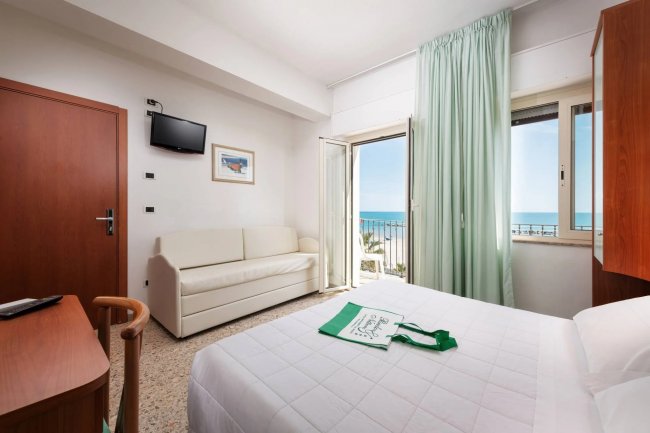 Camera con letto, divano, TV e vista mare.