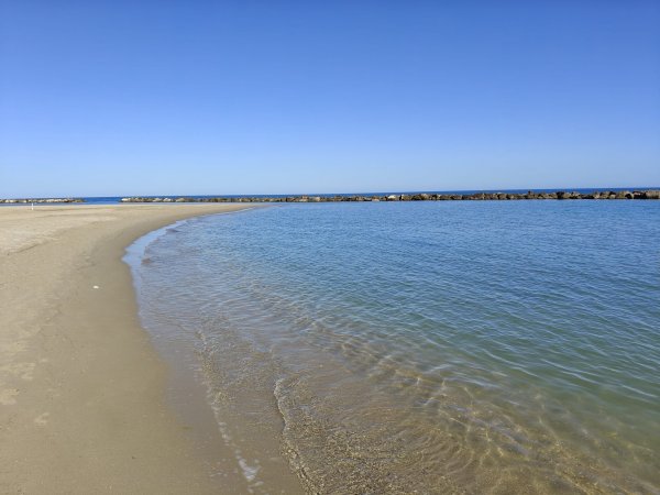 Spiaggia con mare calmo e cielo sereno.