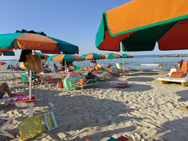 Spiaggia con ombrelloni e lettini colorati.
