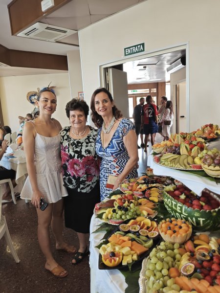 Tre persone davanti a un buffet di frutta.
