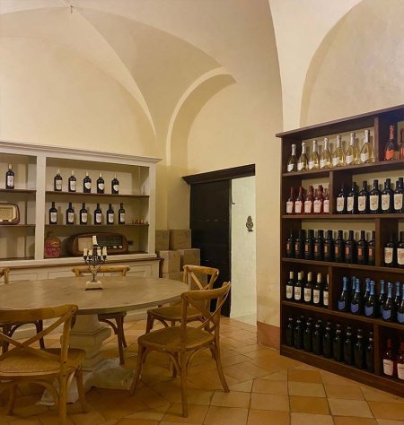 Sala con tavolo rotondo e scaffali di vini.