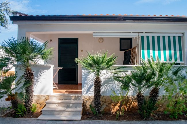 Veranda con palme e tende verdi.