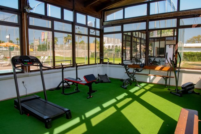 Palestra con attrezzi fitness, vista esterna soleggiata.