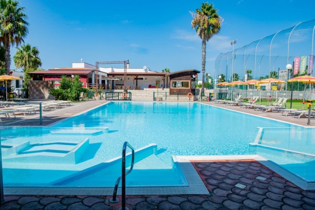 Piscina con lettini e ombrelloni arancioni.