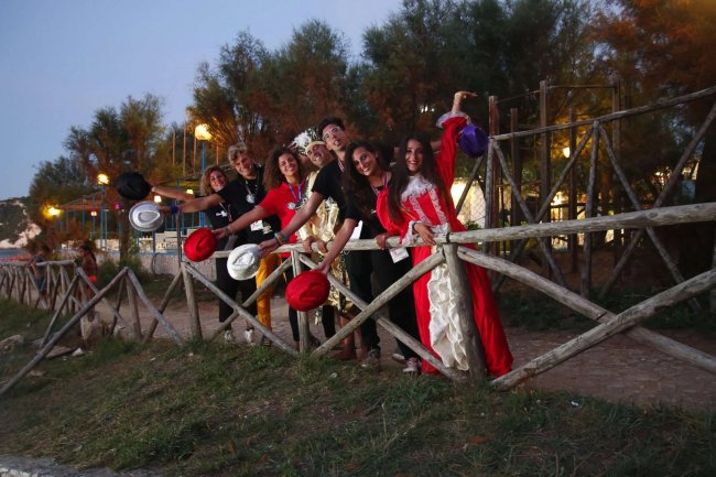 Gruppo di persone con cappelli in posa dietro una staccionata di legno.