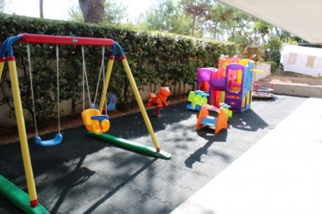 Parco giochi con altalene e scivolo colorato.