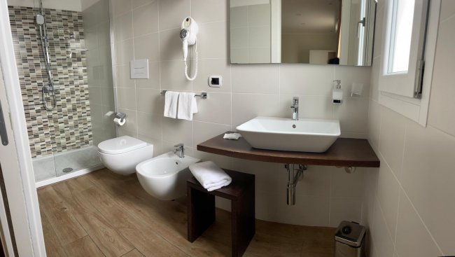 Bagno moderno con doccia, bidet e lavabo bianco.