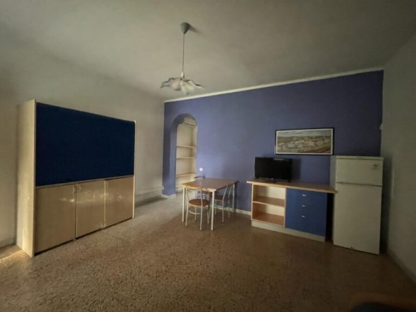 Sala con parete viola, tavolo e frigorifero.