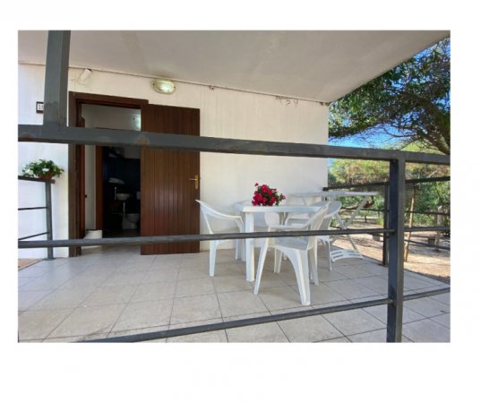 Veranda con tavolo bianco e sedie di plastica.