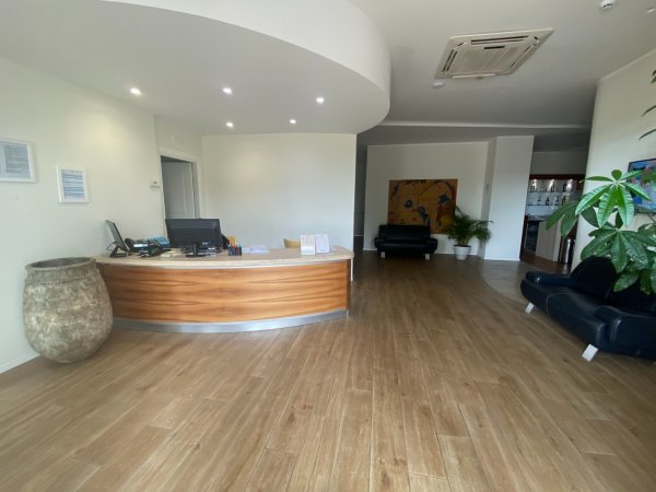 Una reception con pavimento in legno e divani neri.