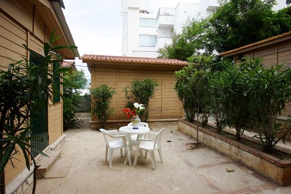 Cortile con tavolo bianco e sedie circondato da piante.