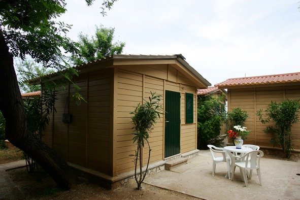 Una casetta in legno con tavolo e sedie.