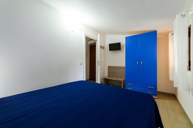 Camera con armadio blu e letto matrimoniale.