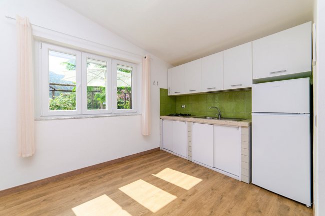 Cucina luminosa con mobili bianchi e parete verde.