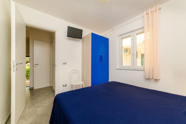 Camera con armadio blu e televisione.