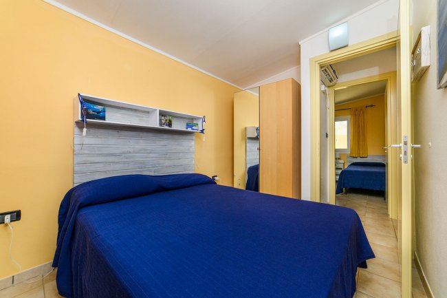 Camera con letto matrimoniale e parete gialla.