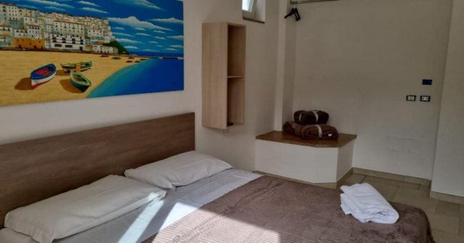Camera con letto matrimoniale e quadro di spiaggia.