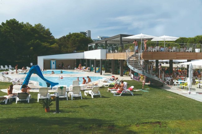 Piscina all'aperto con scivolo e sdraio.